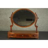 A George III mahogany toilet mirror, with an oval bevelled mirror plate in a swivel frame, over a