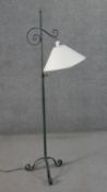 A Victorian style wrought iron standard lamp with a verdigris finish, a cream coloured shade, on