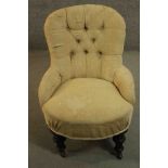 A Victorian nursing chair, upholstered in beige fabric with buttoned back and arms, on turned