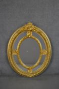 A Victorian gilt framed oval mirror, with a sectional mirror plate in an ornately moulded frame with