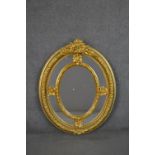 A Victorian gilt framed oval mirror, with a sectional mirror plate in an ornately moulded frame with