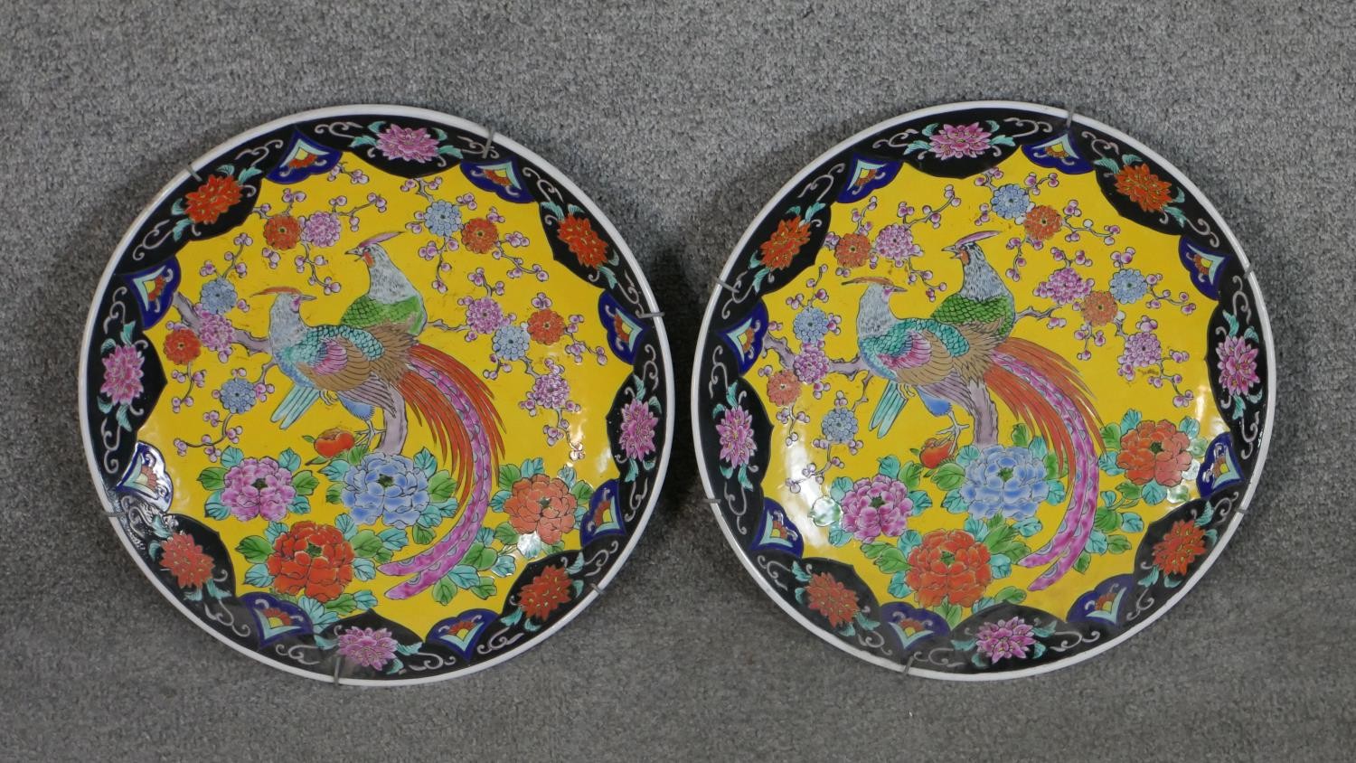 A pair of 20th century Chinese Famille Rose chargers with pheasant among flowers design on yellow