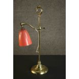 An Edwardian brass adjustable desk lamp with orange bell shaped shade. H.58 W.23cm.