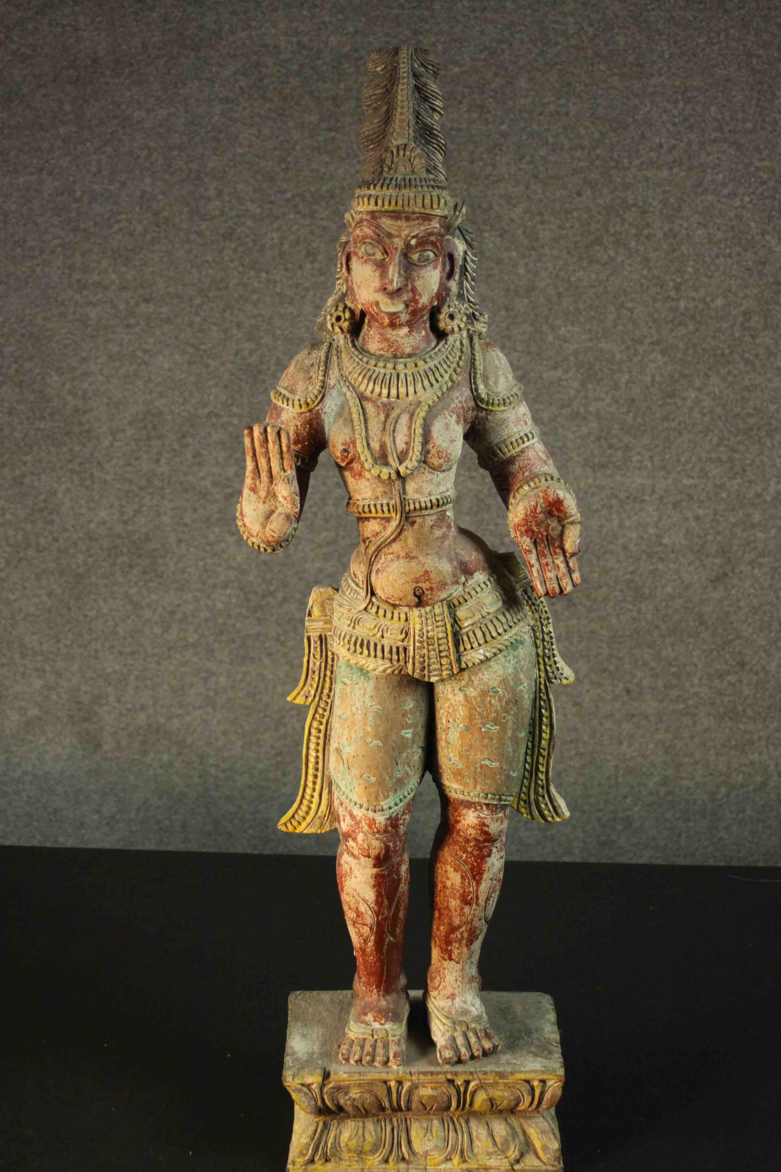 A large carved and painted 19th century Oriental statue of a deity standing on a rectangular lotus