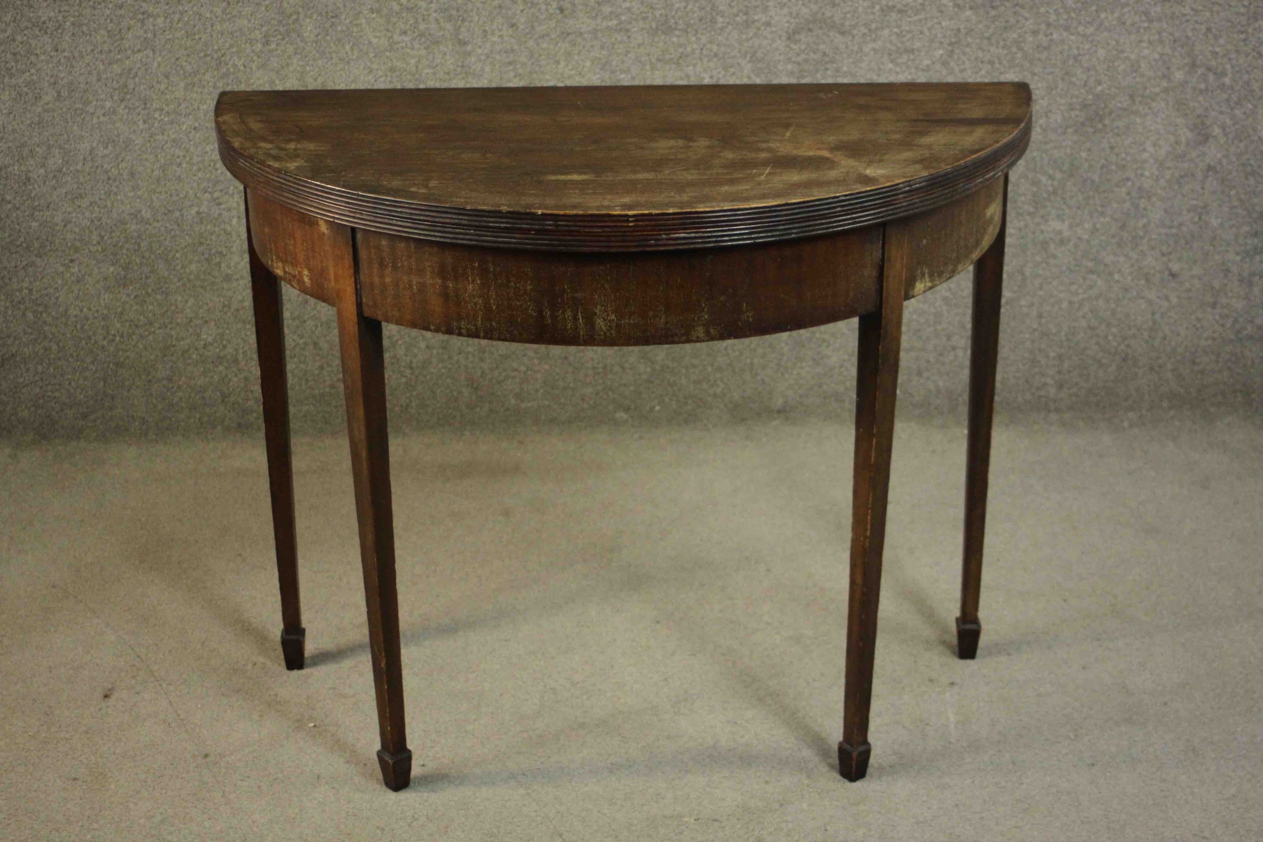 A George III mahogany demi-lune tea table, with a moulded edge and foldover top on square section