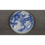 A large Japanese 19th century hand painted blue and white ceramic charger depicting a hawk in a pine