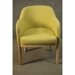 A contemporary beech tub chair, upholstered in tufted yellow fabric raised on square section