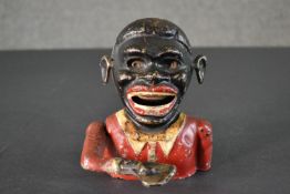 A vintage painted cast iron hand operating money box of an African gentleman. H.15 W.12cm