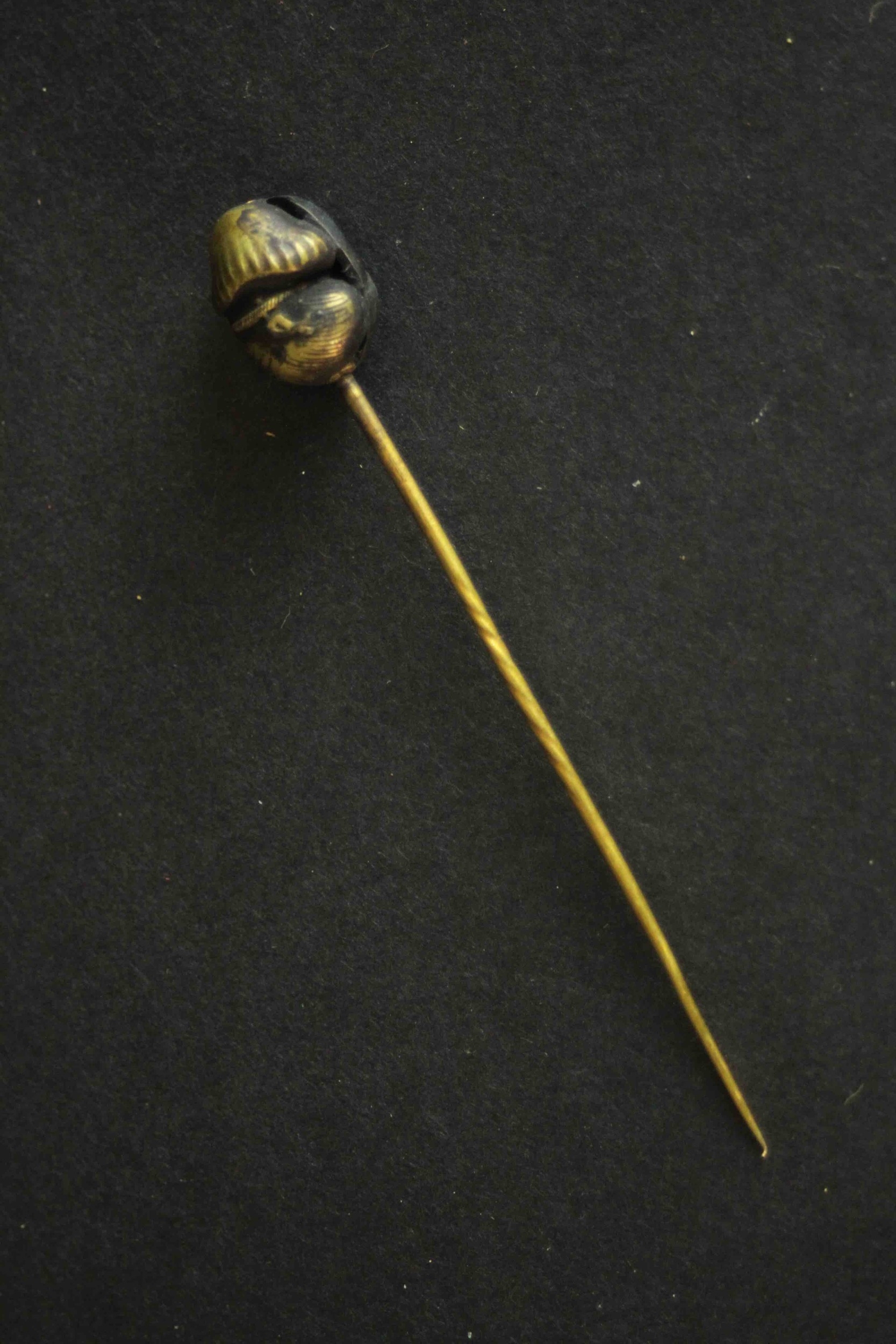A Japanese Meji period Shakudo ware stick pin one side with a man's face and the other side with a