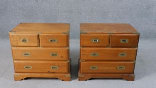 A pair of campaign style bedside chests, of two short over two long drawers with recessed brass