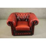 A 20th century red leather Chesterfield armchair, with deep buttoned back, arms and front.