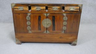 A 20th century Korean elm side cabinet with four short drawers over two cupboard doors with brass