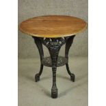 A black painted Victorian cast iron pub table with a circular pitch pine top on three curved legs