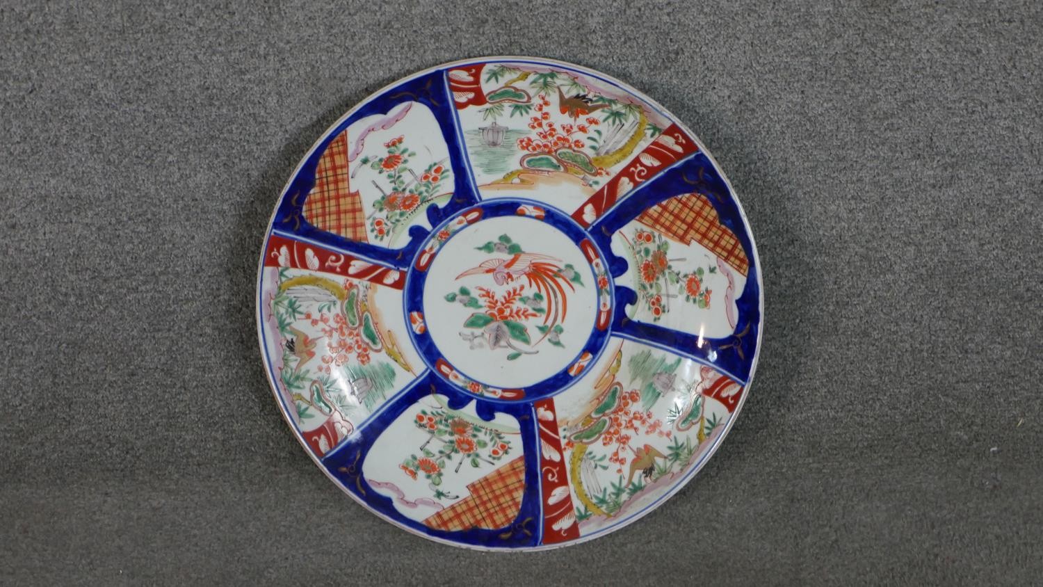 A large 19th century Japanese Imari charger with panels depicting flowers and birds on a dark blue