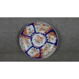 A large 19th century Japanese Imari charger with panels depicting flowers and birds on a dark blue