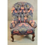 A 19th century French walnut armchair, upholstered in foliate fabric on a blue ground with a