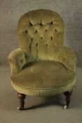 A Victorian armchair, upholstered in green velour with a buttoned back and arms, on turned walnut