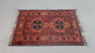 An Ankhoi Afghan rug with central stylised flowerhead medallions on a burgundy ground. L.122 W.80cm