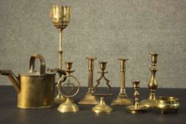 Three brass candle holders and a brass 19th century watering can along with four brass candle