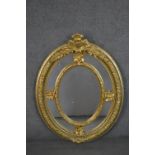 A Victorian gilt framed oval mirror, with a sectional mirror plate in an ornately moulded frame with