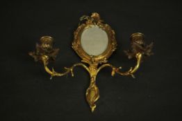 An early 20th century gilt brass Rococo style girandole with an oval mirror and two scrolling arms