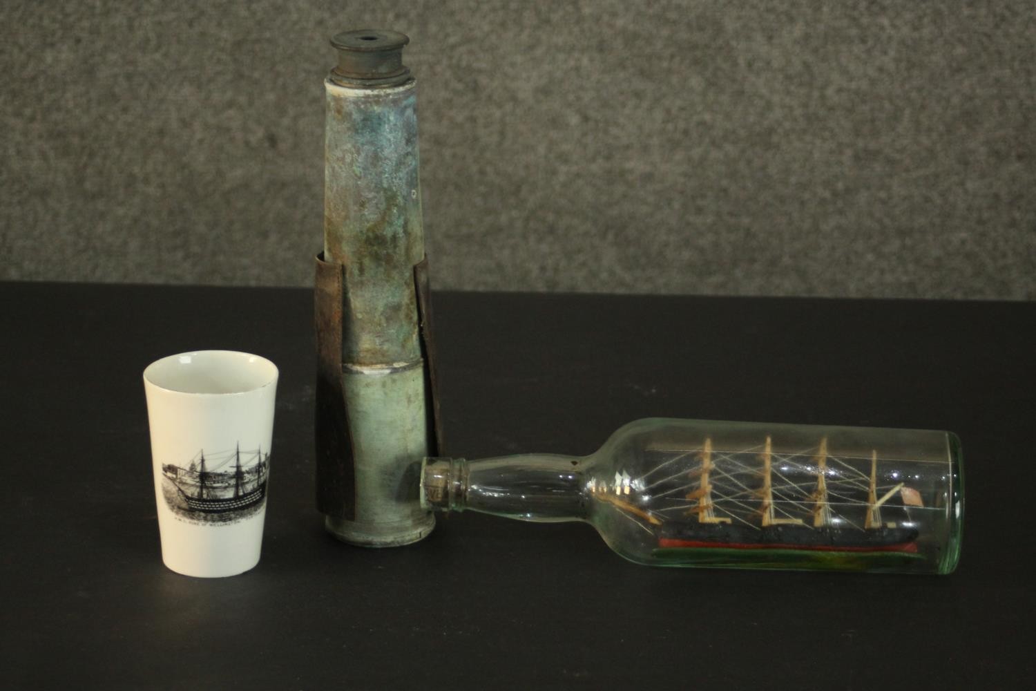 A carved and painted ship in a bottle along with a telescope and a transfer printed ship design