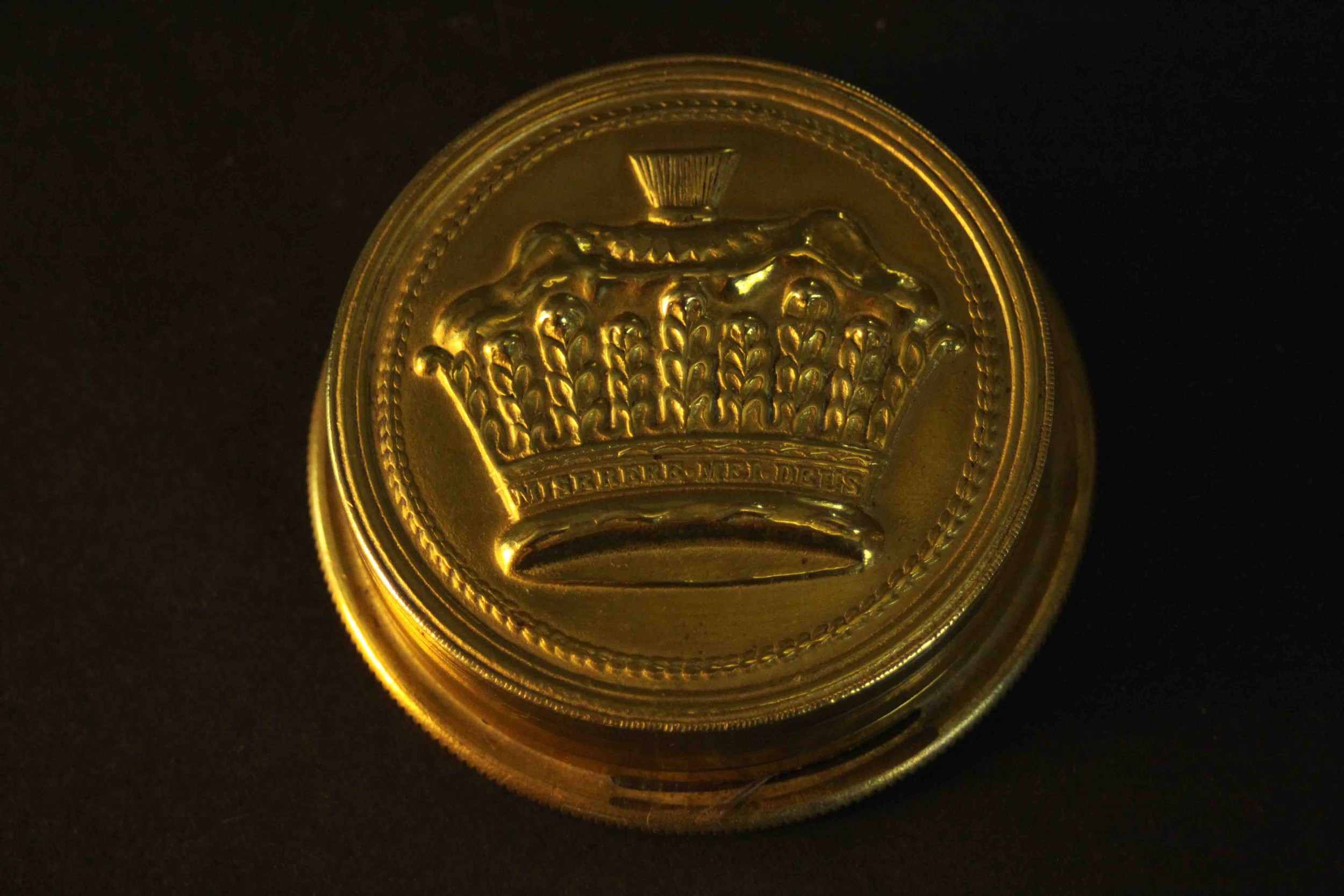 An early 20th century brass embossed box containing an Irish clerical wax seal. H.2.5 Dia.8cm.