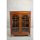 An early to mid-20th century fruitwood display cabinet, the two glazed doors enclosing shelves on