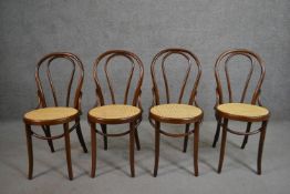 A set of four Thonet style bentwood café chairs with a curved back on a circular caned seat.