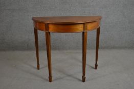 A George III style mahogany demi-lune side table on square section tapering legs terminating in