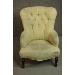 A Victorian mahogany armchair, upholstered in buttoned yellow fabric, on turned legs.