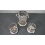 A pair of silver plated pierced design wine coasters and a similar twin handled bottle holder. H.
