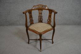 An Edwardian walnut corner chair with a carved back rail over pierced splats over a patterned seat