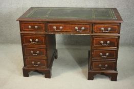 A 20th century mahogany pedestal desk, with a tooled green leather writing surface, over an