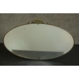 An early 20th century oval mirror in a brass frame and a vine crest. H.45 W.69cm.