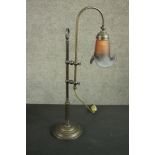 An Edwardian style brass desk lamp with polychrome glass shade on an adjustable mount and a circular