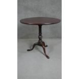 A George III mahogany tilt top tripod table with a circular top on a turned and wrythen stem with