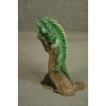 A hand painted clay figure of a green Iguana perched on a branch. H.53cm.