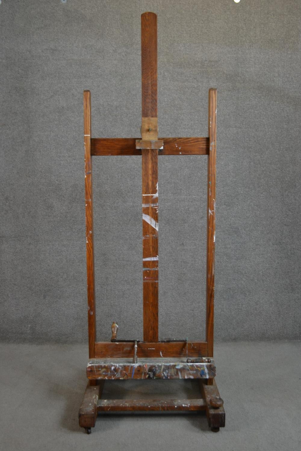 A late 19th/early 20th century oak artist's studio easel, with winders for raising and lowering