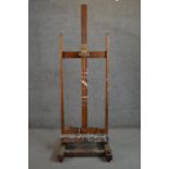 A late 19th/early 20th century oak artist's studio easel, with winders for raising and lowering