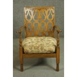 A circa 1920's beech open armchair with an ornate pierced back over curved arms, above an