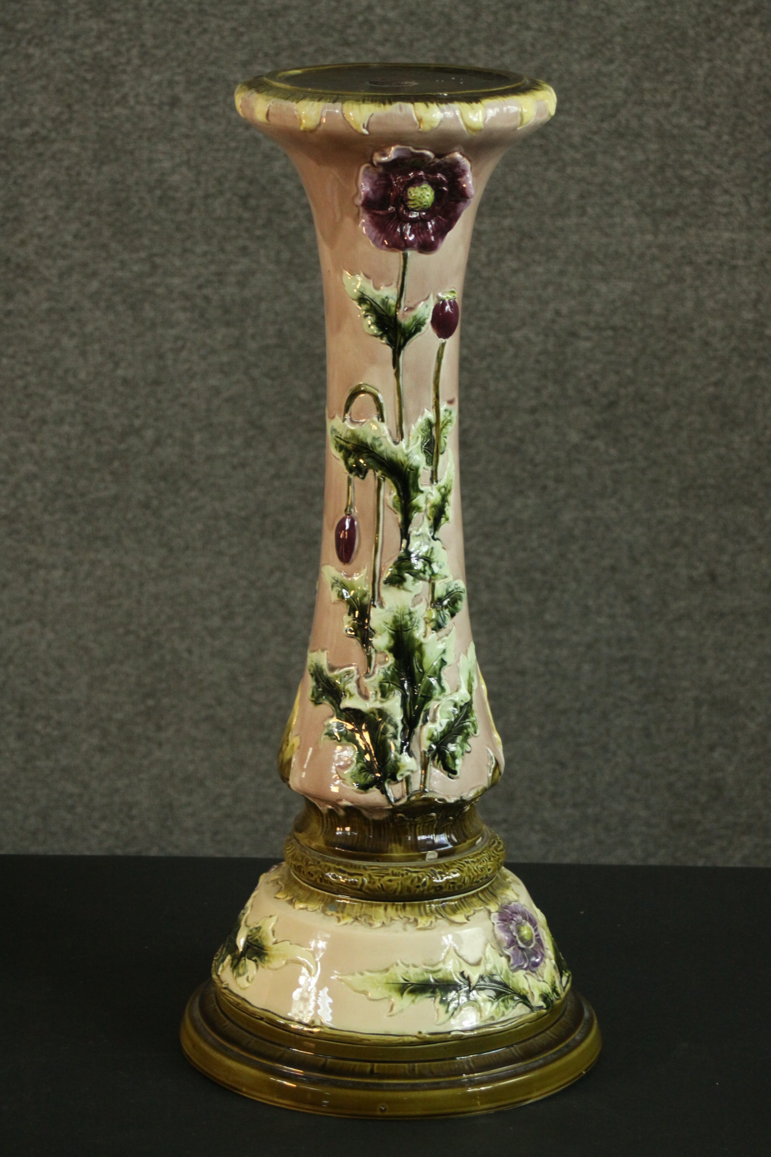 An early 20th century relief poppy design ceramic planter stand on cream ground and green detailing.