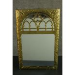 A Gothic Revival/Arts & Crafts planished brass framed mirror with gothic tracery to the rounded arch