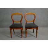 A pair of Victorian walnut saddle back dining chairs, the serpentine seats upholstered in grey
