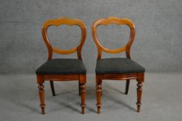 A pair of Victorian walnut saddle back dining chairs, the serpentine seats upholstered in grey