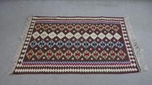 A handmade maroon ground Kelim rug with geometric design. L.147 D.101cm