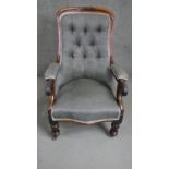 A Victorian walnut open armchair upholstered in grey fabric with a buttoned back over a serpentine