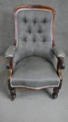 A Victorian walnut open armchair upholstered in grey fabric with a buttoned back over a serpentine