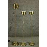 A set of three contemporary brass floor standing lamps, including an adjustable reading lamp and a