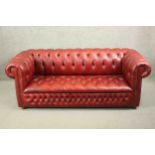 A red leather Chesterfield sofa, buttoned to the back, arms, seat, and front, on bun feet. H.75 W.